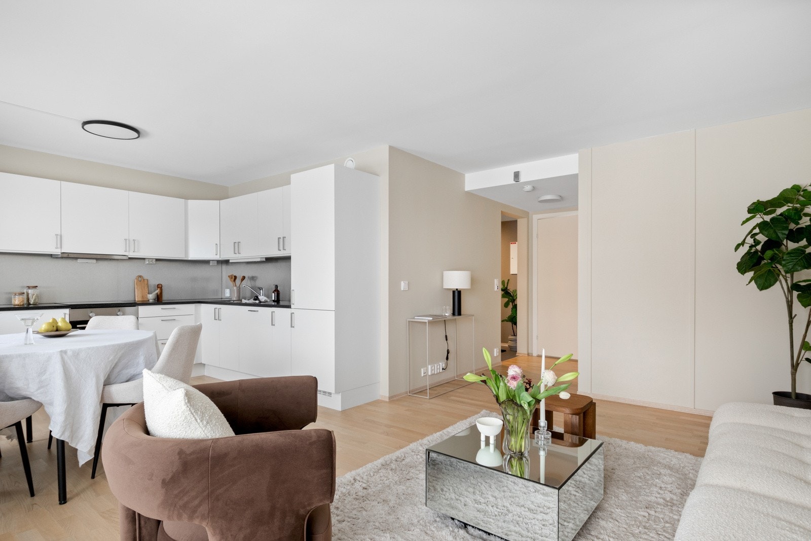 Innredningen fra Sigdal har hvite, glatte fronter, sort benkeplate i laminat med nedfelt vaskekum og grå, metalliske plater som backsplash. Galleribilde