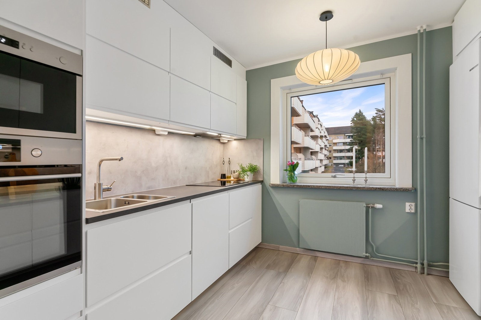 Kjøkkenet ligger i eget rom med stilren, takhøy innredning, enstavs laminatgulv og pent malte vegger. Galleribilde