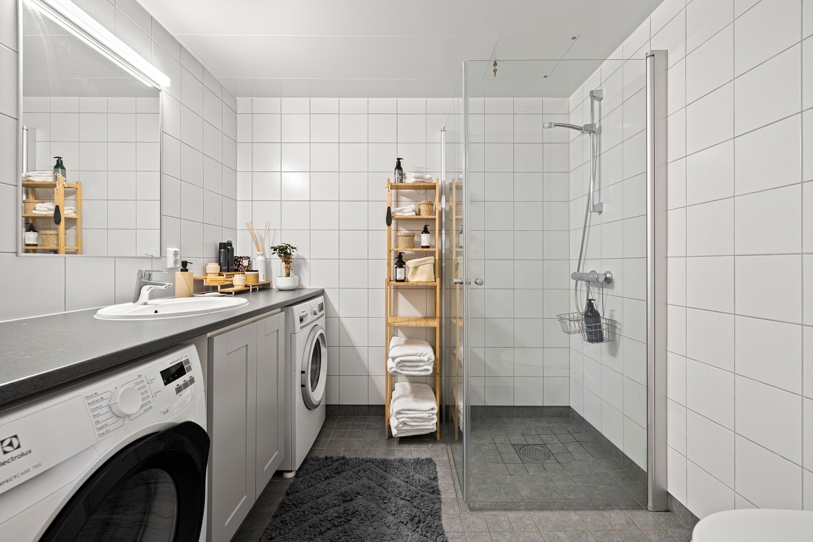 Romslig baderom med moderne innredning og praktisk oppbevaring. Stilrene fliser, gulvvarme og god belysning skaper en behagelig atmosfære. Galleribilde