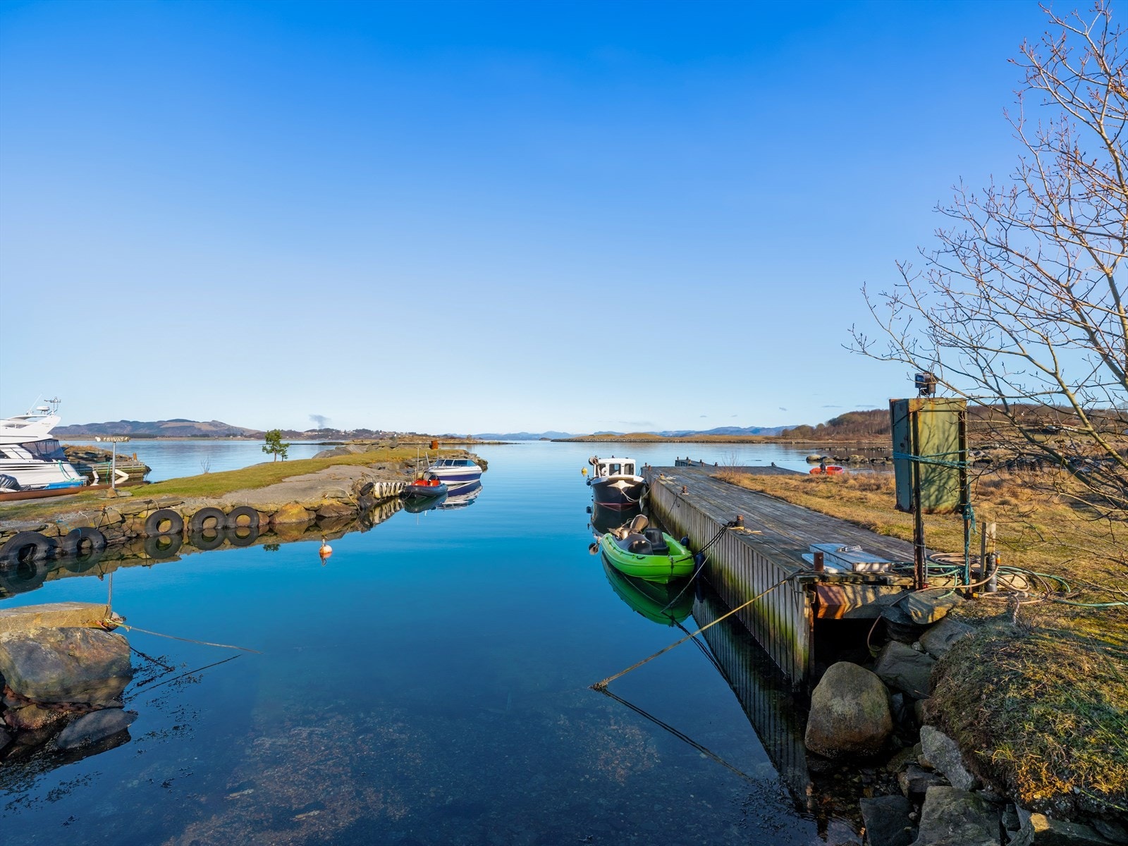 Idyllisk sjøutsikt med flere båtplass i naturskjønne omgivelser. Perfekt for båtentusiaster og de som søker ro og naturopplevelser. Galleribilde