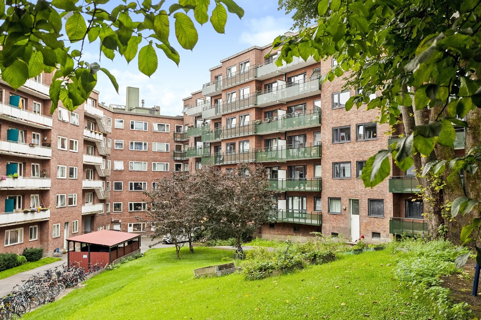 Pent opparbeidet med gressarealer, heller, prydbusker, hekker, trær, sykkelstativ, lekeapparater, benker, bord og asfalterte gangveier. Galleribilde