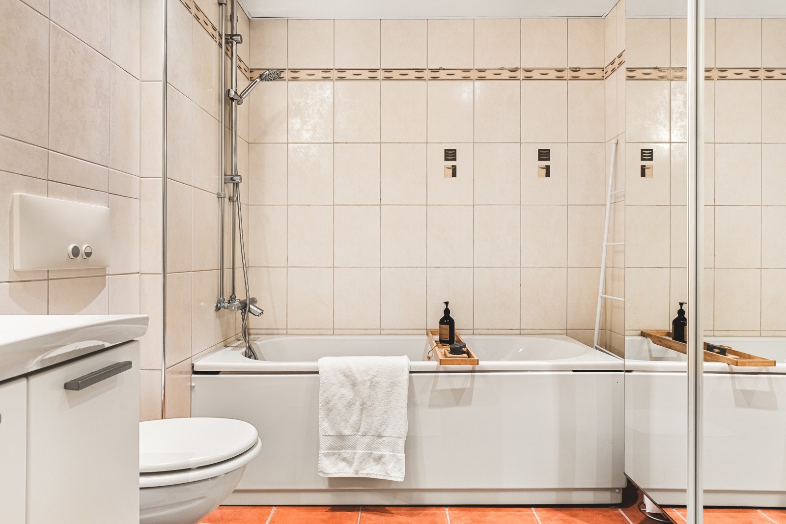 Badet er innredet med vegghengt toalett, badekar, servantmøbel med speilskap og opplegg for vaskemaskin. Galleribilde