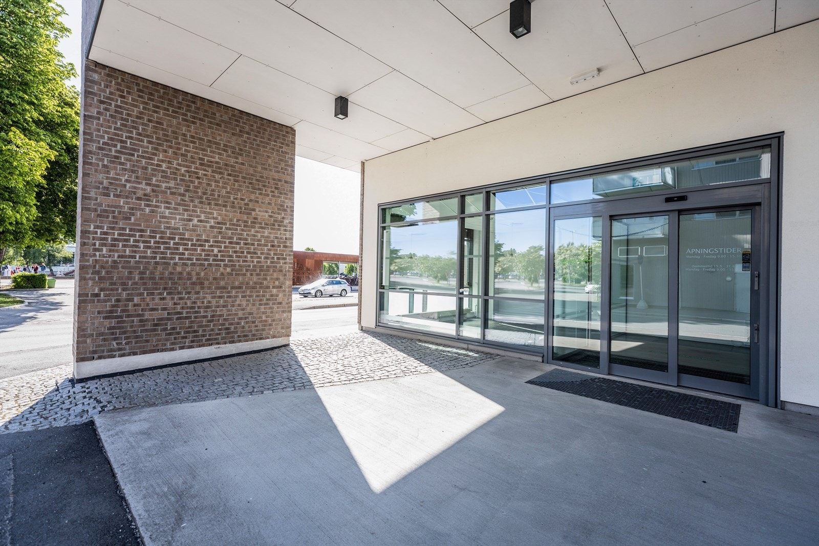 Overbygget inngangsparti og store glassflater mot gateplan. Galleribilde