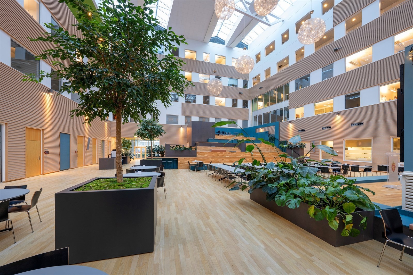 Lys og moderne atrium med store vinduer og grønne innslag. Galleribilde