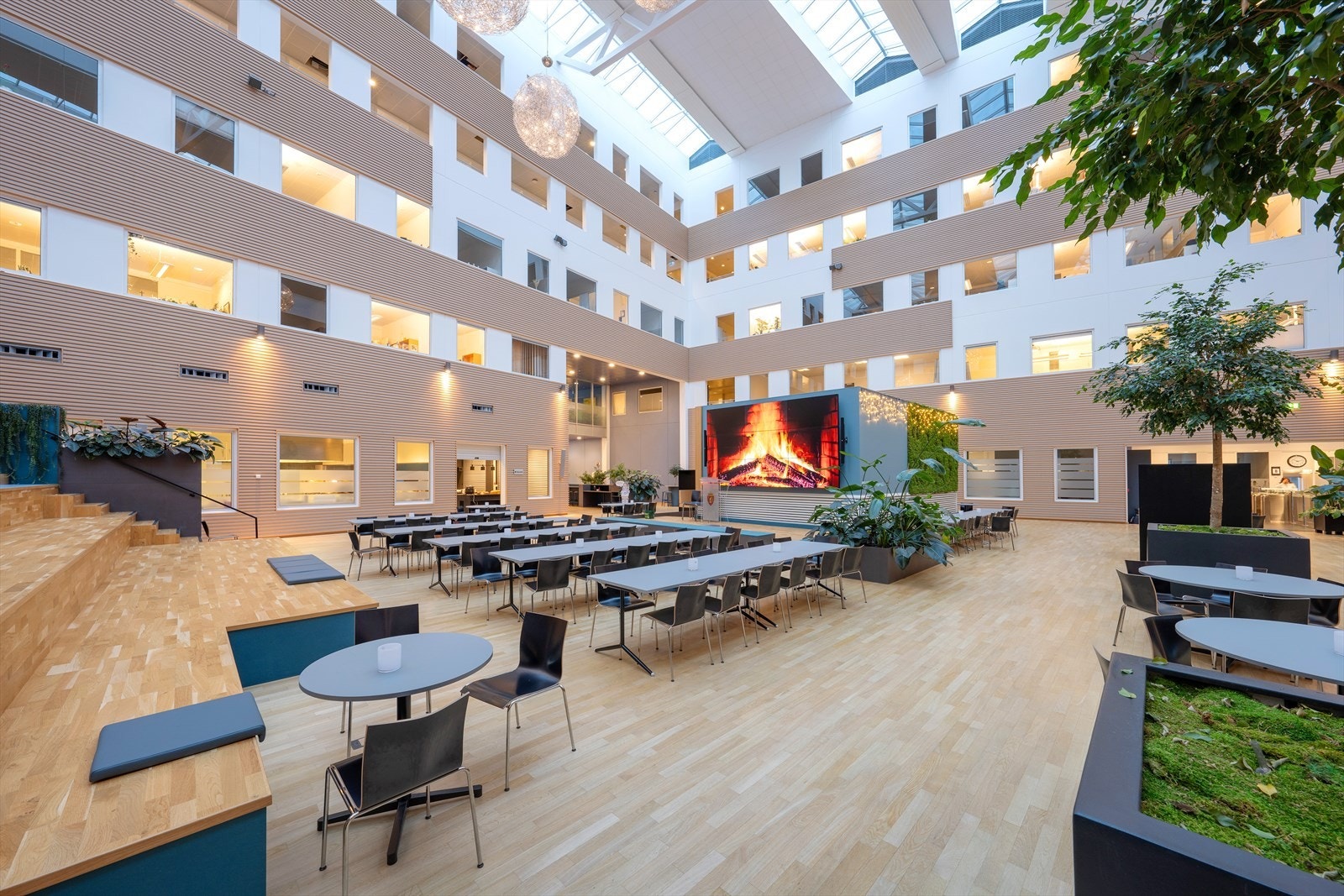 Lyst og moderne fellesområde med store vinduer, grønne planter og et innbydende miljø. Galleribilde