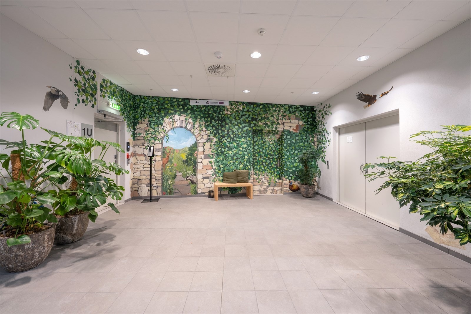 Innbydende inngangsparti med frodig veggkunst malt av elever fra en lokal skole, som skaper en følelse av åpenhet og natur. Galleribilde