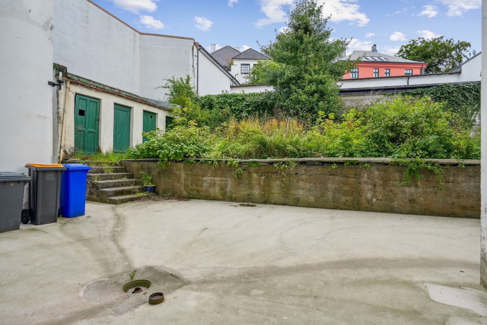 Fra kjøkkenet har man utgang til en romslig bakgård, med betongdekke og noe grøntarealer. Galleribilde