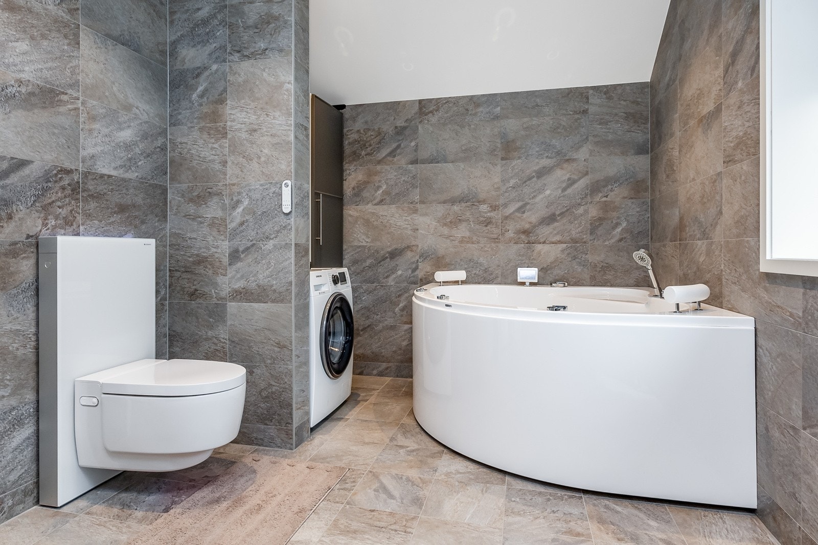 Hovedbadet som er flislagt og har installert både boblekar og dusjsone. I tillegg toalett. Opplegg til vaskemaskin. Galleribilde