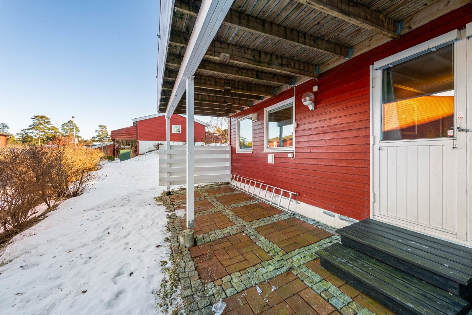 Terrasse under balkongen med dør til hovedsoverommet. Det er lys og stikkontakt på veggen. Galleribilde