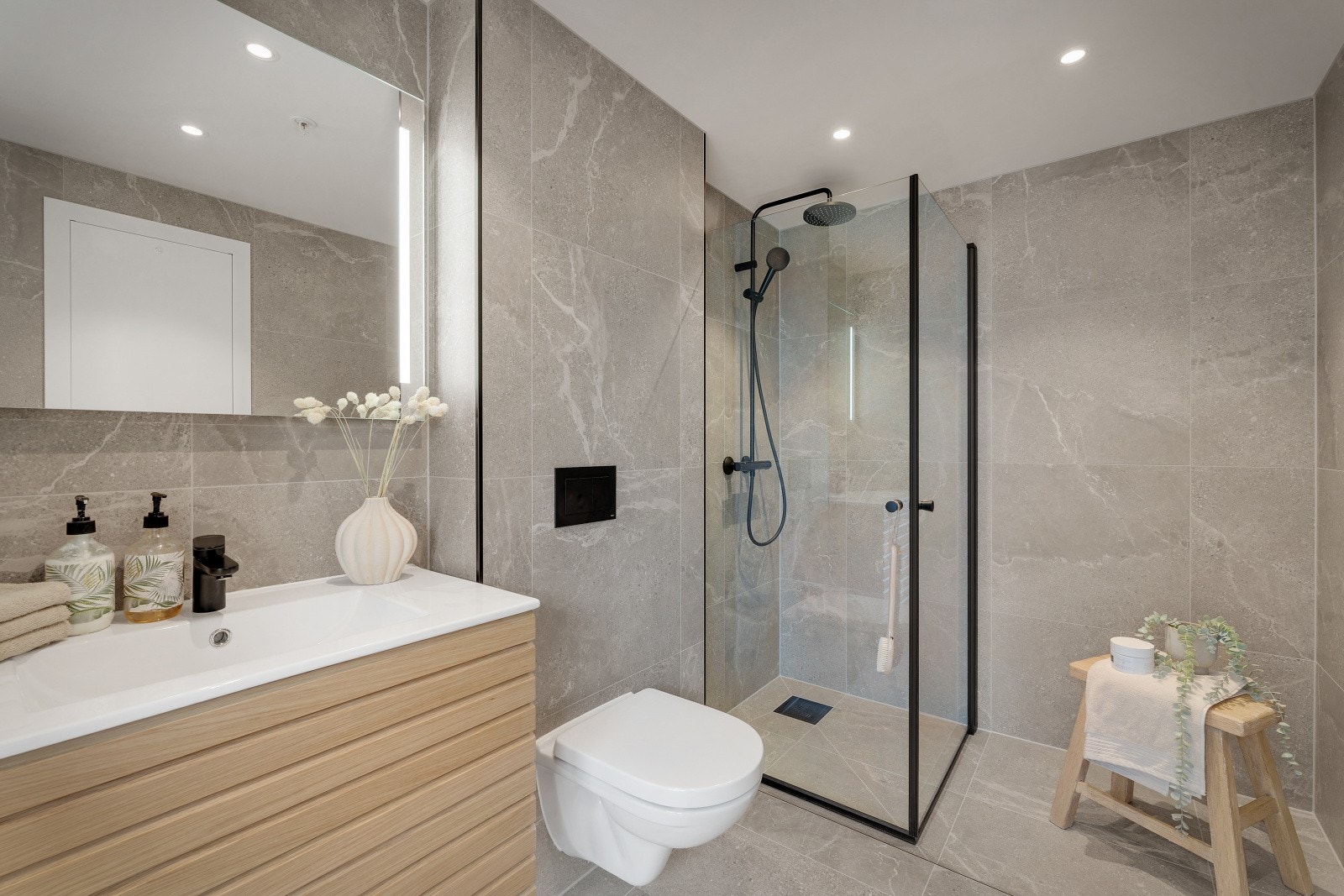 Badet er innredet med baderomsmøbel med heldekkende servant, speil med lys, dusj med glassvegger og vegghengt toalett. Galleribilde