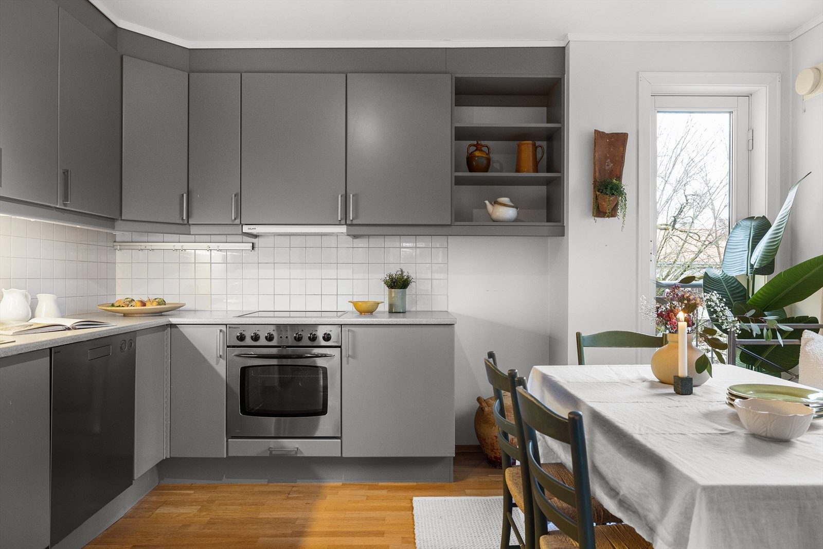 Kjøkkeninnredning med glatte, malte fronter og benkeplate i laminat med kum og ett-greps blandebatteri. Det er flislagt på vegg over kjøkkenbenk. Galleribilde