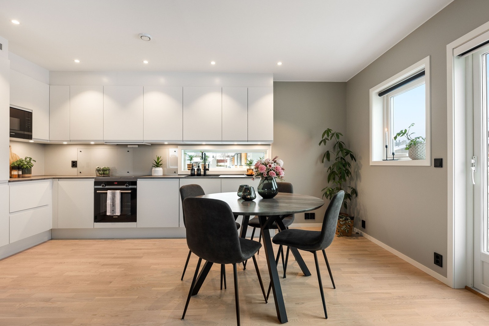 Lyst og moderne kjøkken med integrerte hvitevarer og god skapplass. Store vinduer gir rikelig med naturlig lys. Galleribilde