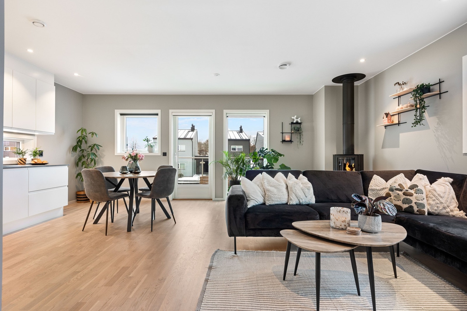 Stue med åpen kjøkkenløsning. Store vinduer og balkongdør som gir rikelig med naturlig lys. Peisovn skaper en lun atmosfære. Galleribilde