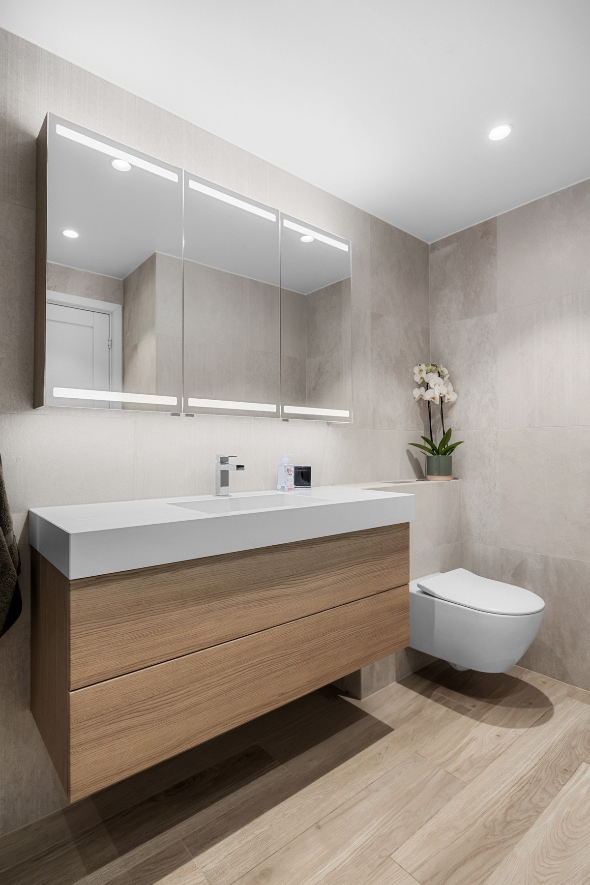 Servantskap og speilskap med lysarmatur gir lagringsmuligheter for toalettartikler, mm. Badet har veggmontert toalett. Galleribilde