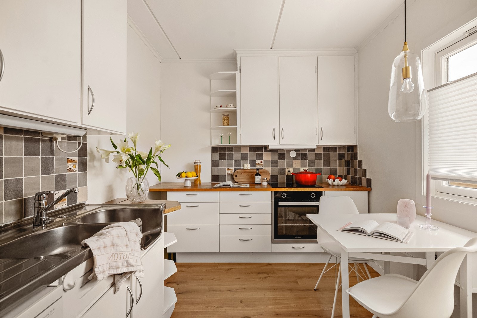 Kjøkkeninnredning fra IKEA med hvitmalte fronter, benkeplate i heltre, stålvask med skyllekum og ett-greps blandebatteri. Galleribilde