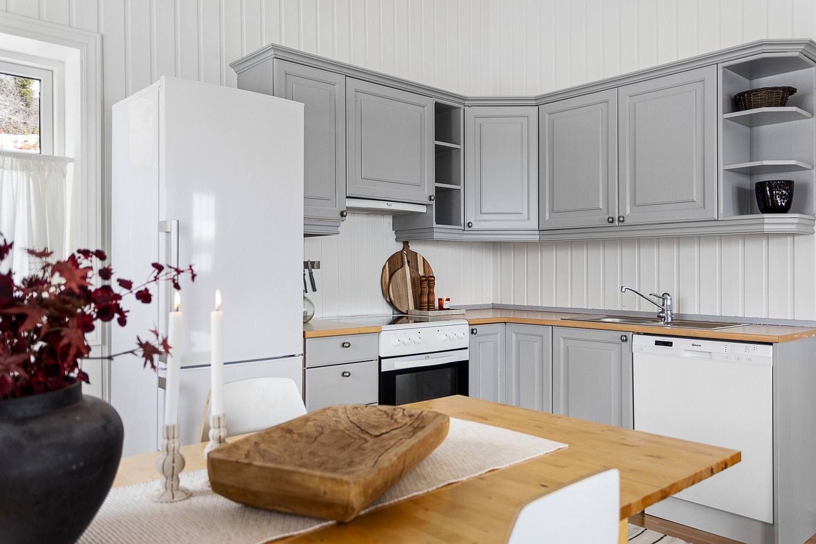 Koselig og velholdt kjøkken med hvitevarer som kjøleskap med frysedel, komfyr og oppvaskmaskin Galleribilde