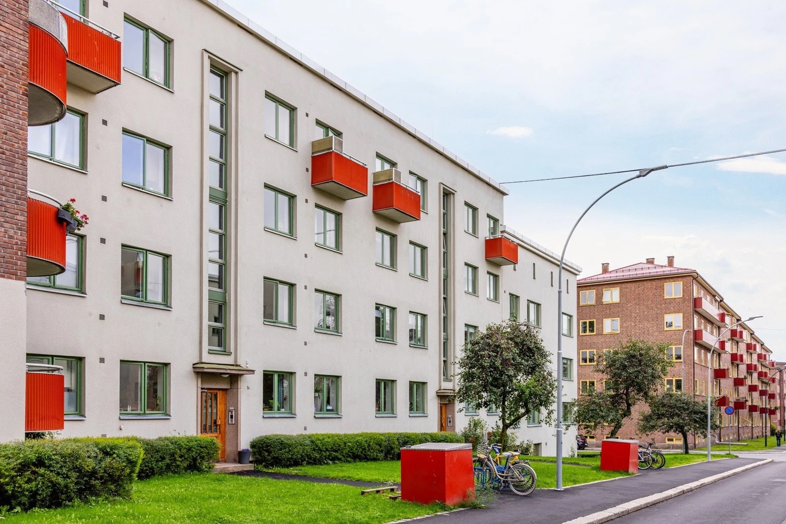 Flott fasade med forhager bestående av gressplen, beplanting, trær og sykkelparkering Galleribilde