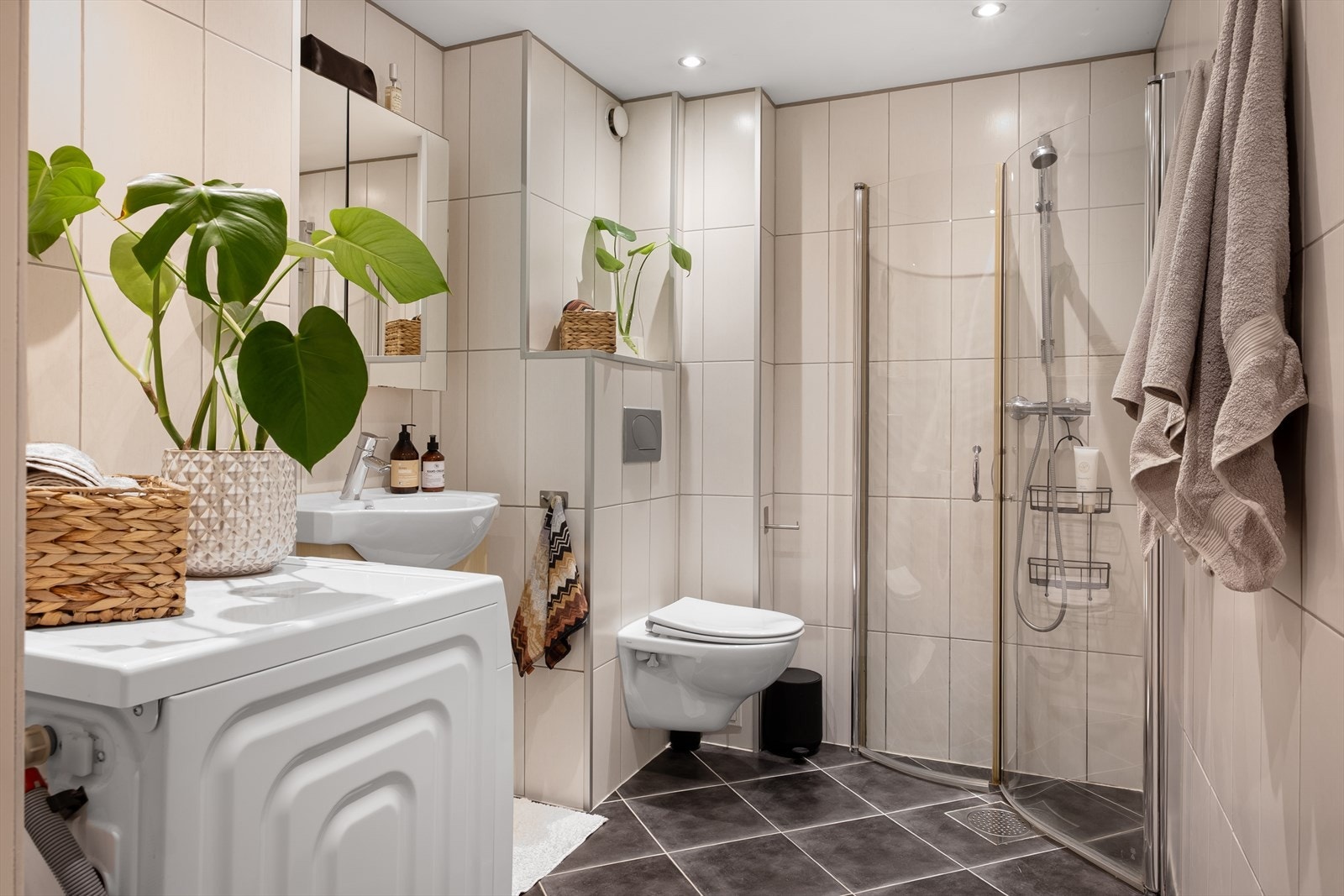 Baderommet er innredet med vegghengt klosett, servant nedfelt i innredning og dusjhjørne med svingbare glassdører Galleribilde