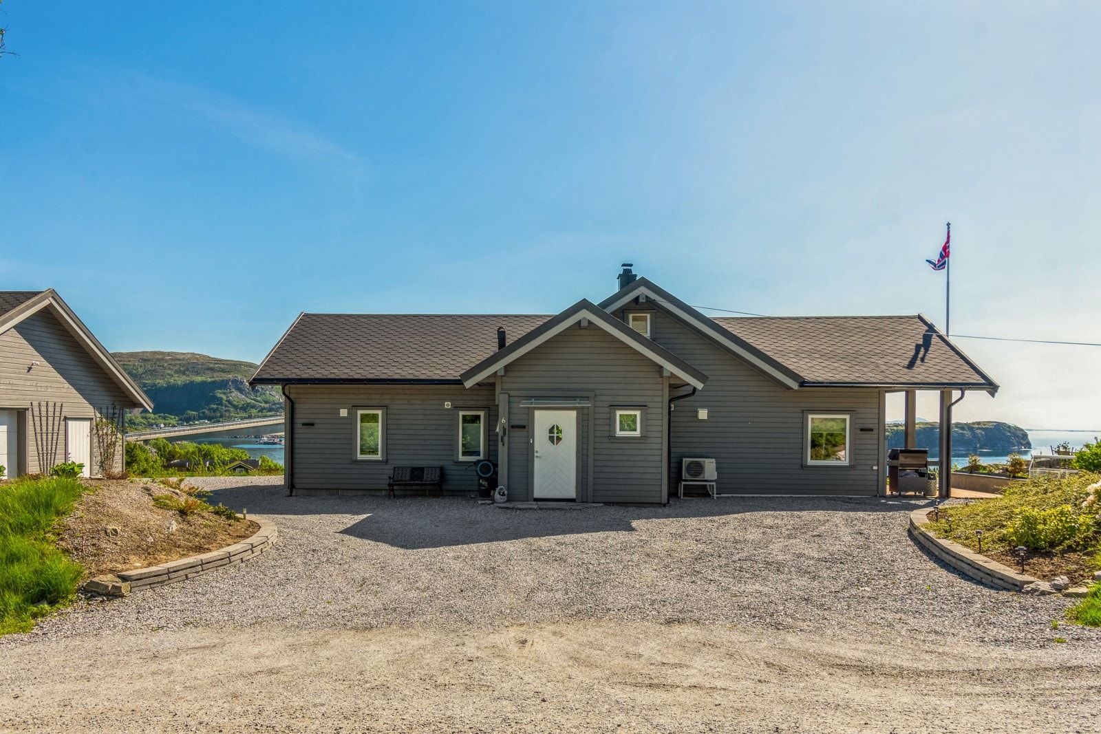 Tomten er pent opparbeidet med bed, flaggstang og gruslagte arealer. Galleribilde