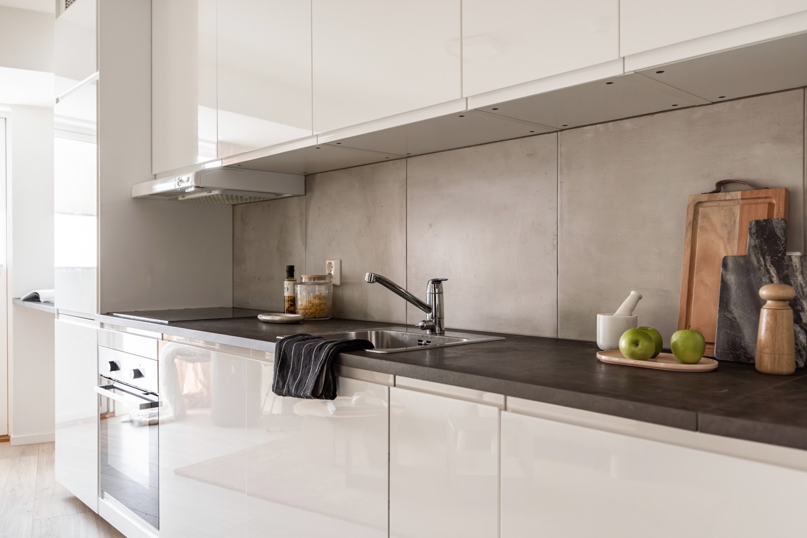 Innredningen har hvite glatte fronter med soft-close og laminert benkeplate med nedfelt oppvaskkum. Praktisk med fliser i benkeryggen, takhøye overskap og downlights i himlingen. Galleribilde