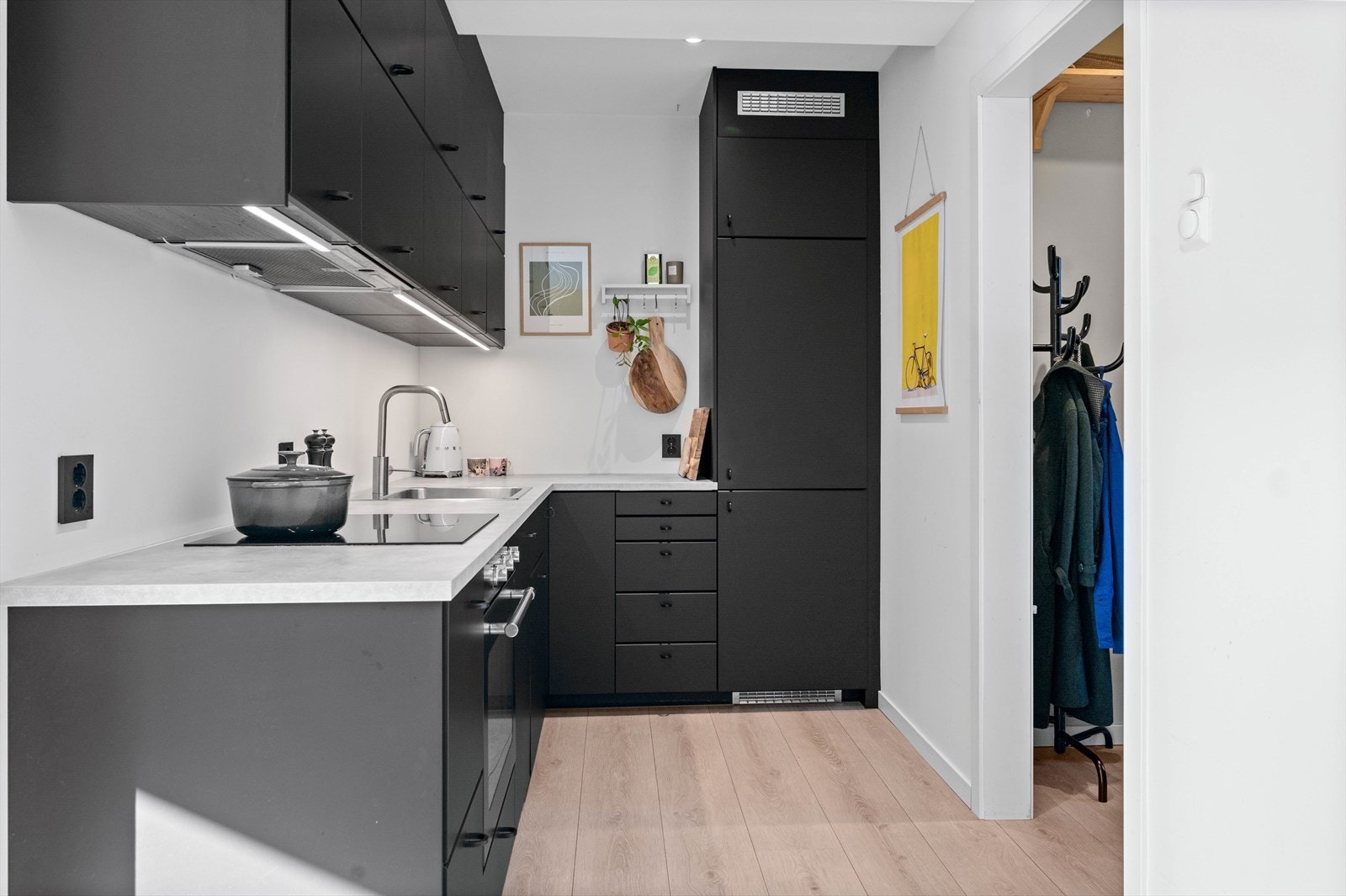 Kjøkkenet har integrerte hvitevarer, kullfiltervifte og belysning under overskapene. Galleribilde