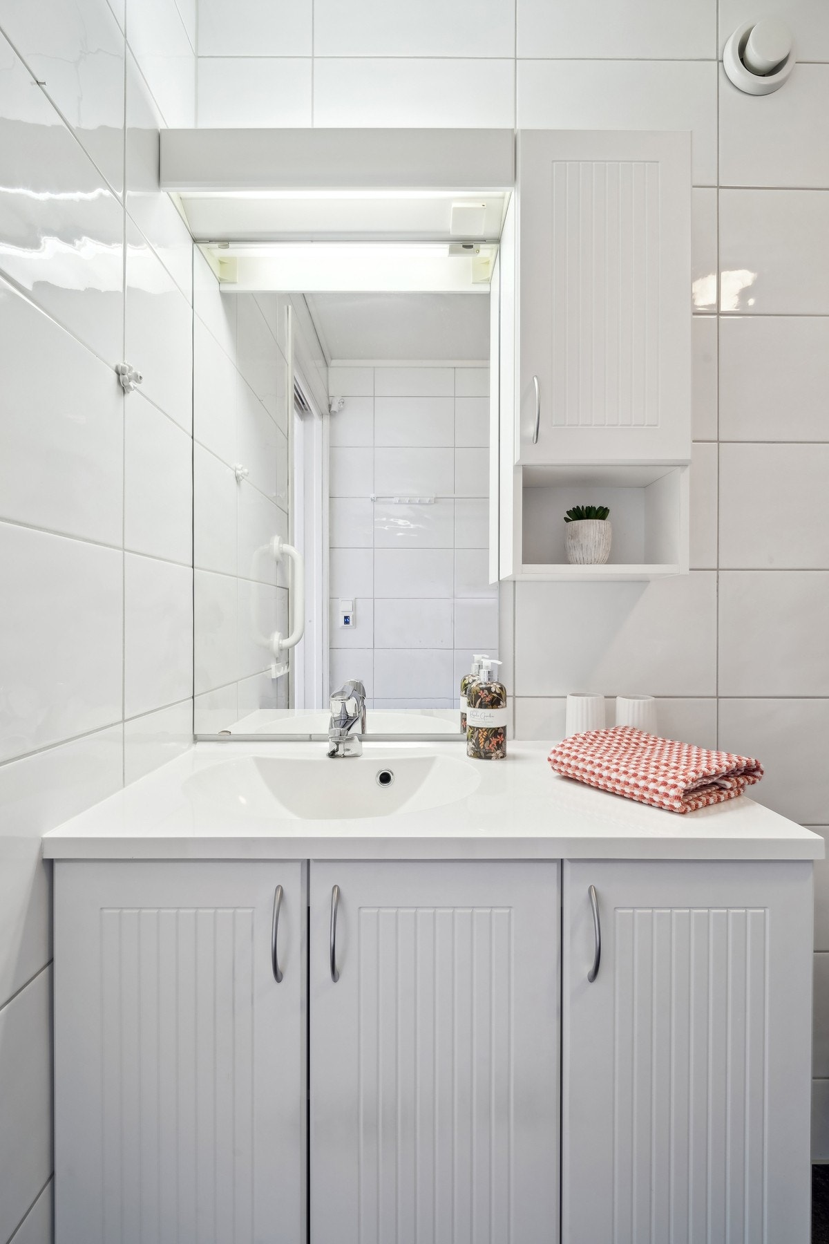 Innredning med profilerte skapdører og helstøpt servant. Speil og belysning over. Galleribilde