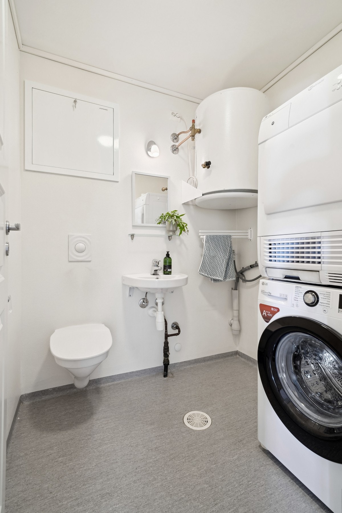 Toalettrom/ vaskerom med vegghengt toalett, servant og opplegg for vaskemaskin og trommel. Vv-tank og vannskap er plassert her. Belegg på gulvet og malte flater på veggene. Galleribilde