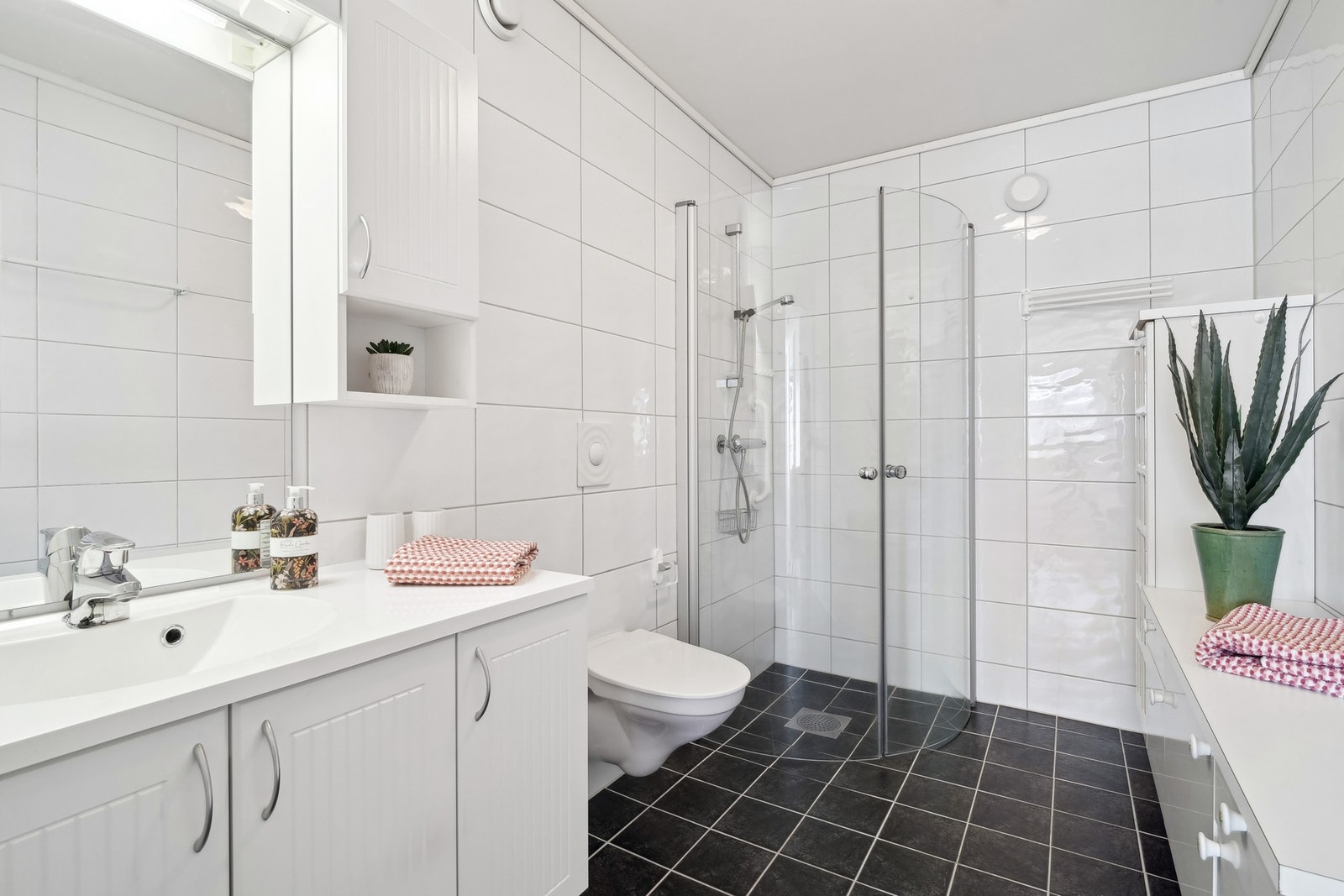 Badet er helfliset med varmekabler i gulvet. Utstyrt med vegghengt toalett og dusjhjørne med glassdører. Ekstra benke innredning gir god plass. Galleribilde