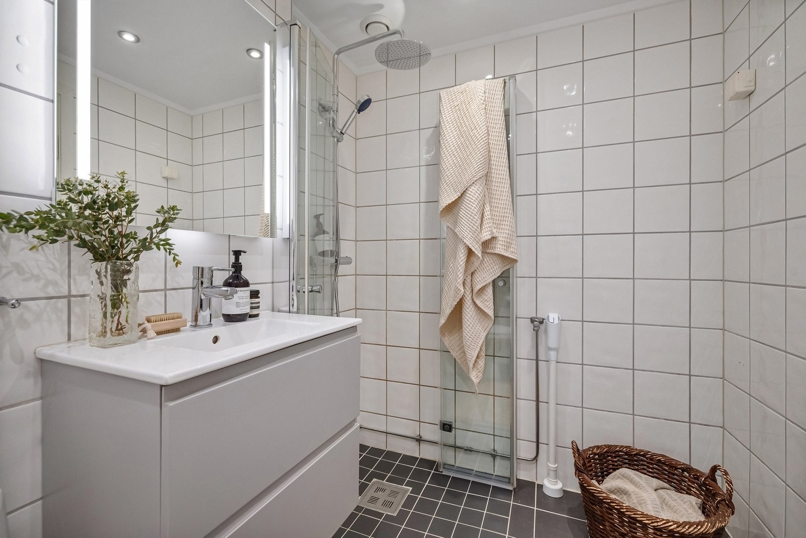 Badet er utstyrt med gulvstående toalett og dusjhjørne med innfellbare glassdører og dusjsett med rainshower Galleribilde