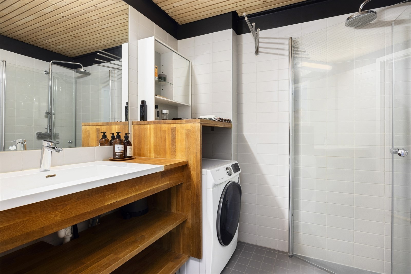 Pent flislagt bad fra 2006. Badet er utstyrt med et dusjhjørne med glassdører, et gulvmontert toalett, en servantinnredning og en plassbygget nisje for vaskemaskin. Galleribilde