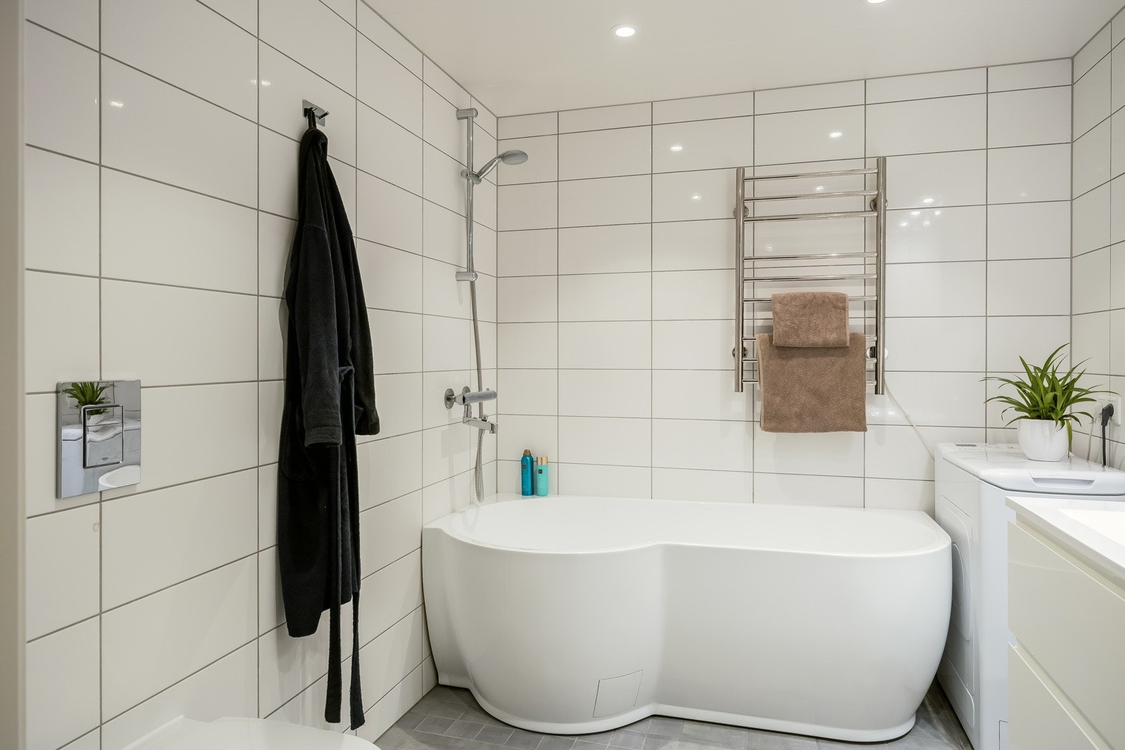 Godt utstyrt med badekar med dusj, opplegg for vaskemaskin, servant med over- og underskap, og vegghengt toalett. Galleribilde