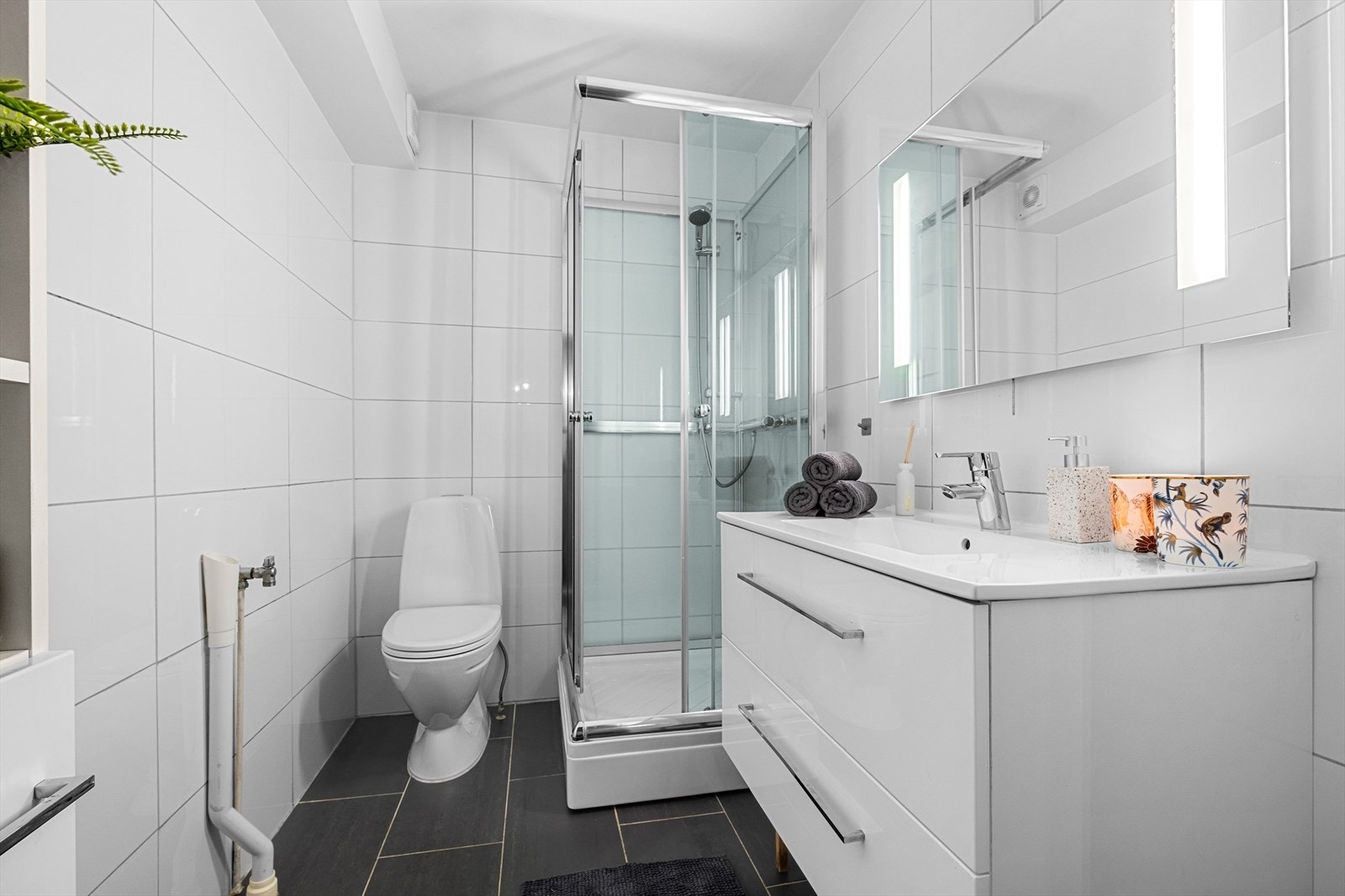 Pent flislagt bad på 3,5m² og er innredet med servantskap med servant, wc, dusjkabinett, mekanisk avtrekk og opplegg for vaskemaskin. Badet ble oppusset i 2014 og frisket opp i 2024 med malt tak, ny vifte og ny termostat til gulvvarmen. Galleribilde