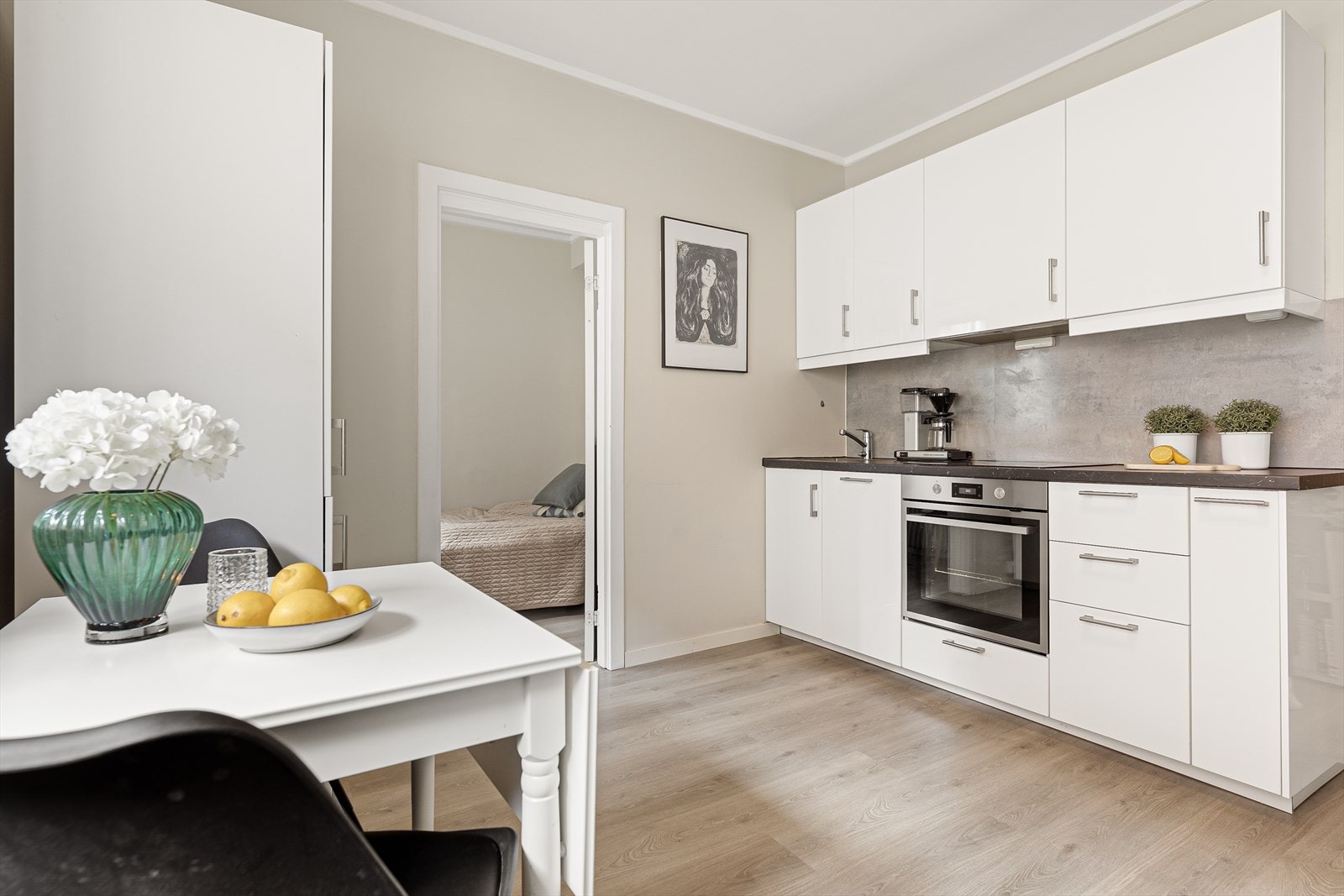 Kjøkkeninnredning fra Ikea (2018) med glatte fronter, laminert benkeplate, oppvaskkum og 1-greps blandebatteri. Integrerte hvitevarer inkludert komfyr, platetopp og smal oppvaskmaskin. Ventilator med kullfilter og komfyrvakt over platetopp. Galleribilde