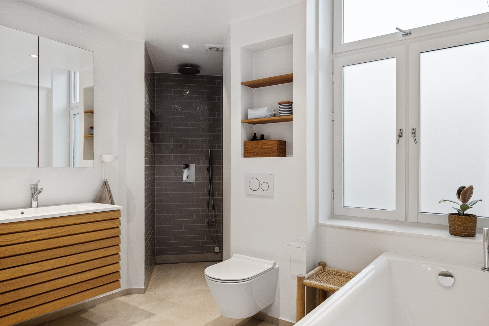 Innbydende flislagt baderom fra 2021 med varmekabler i gulvet og badromsmøbel i heltre eik fra danske Svane. Galleribilde