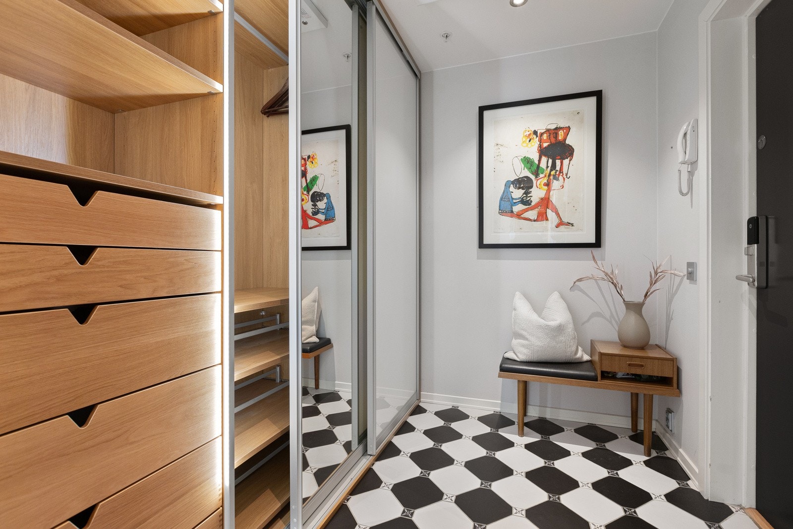 Innbydende inngangsparti som gir et godt førsteinntrykk av leiligheten. Det er god plass til å henge fra seg yttertøy i spesialtilpasset skyvedørsgarderobe fra Poggenpohl med speilfronter og integrert belysning. Galleribilde