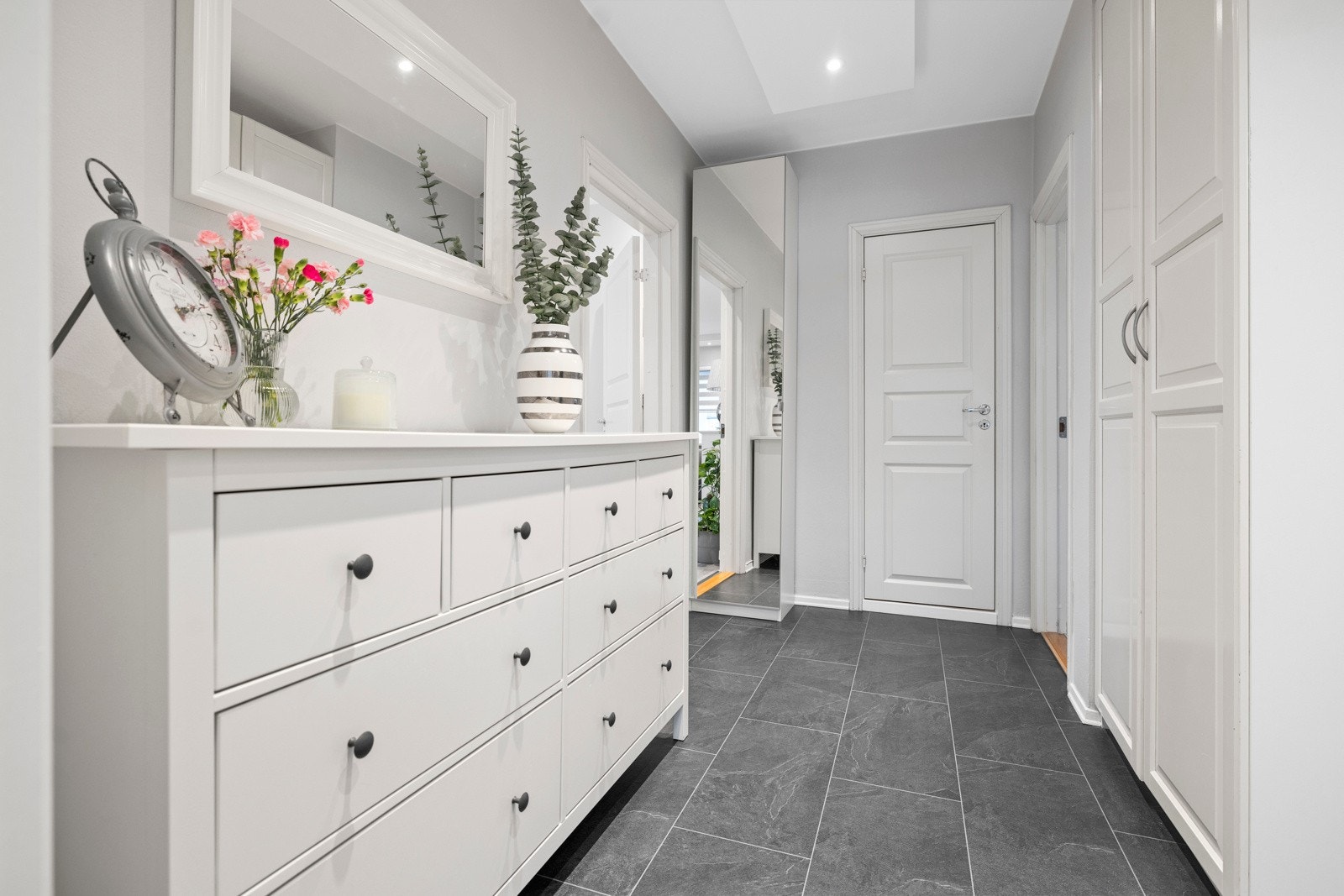 Leiligheten har en romsling entré i lyse farger Galleribilde