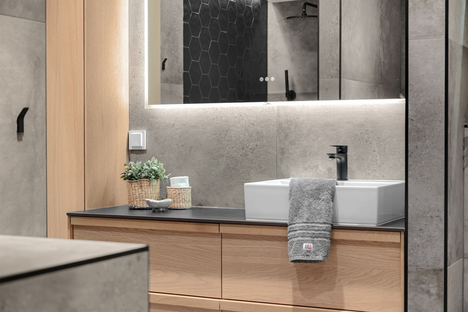 Taket er pent belagt med malte plater og innfelte lys som skaper en sofistikert stemning, mens de mørke, delikate flisene på veggene gir et moderne og tidløst preg. Galleribilde