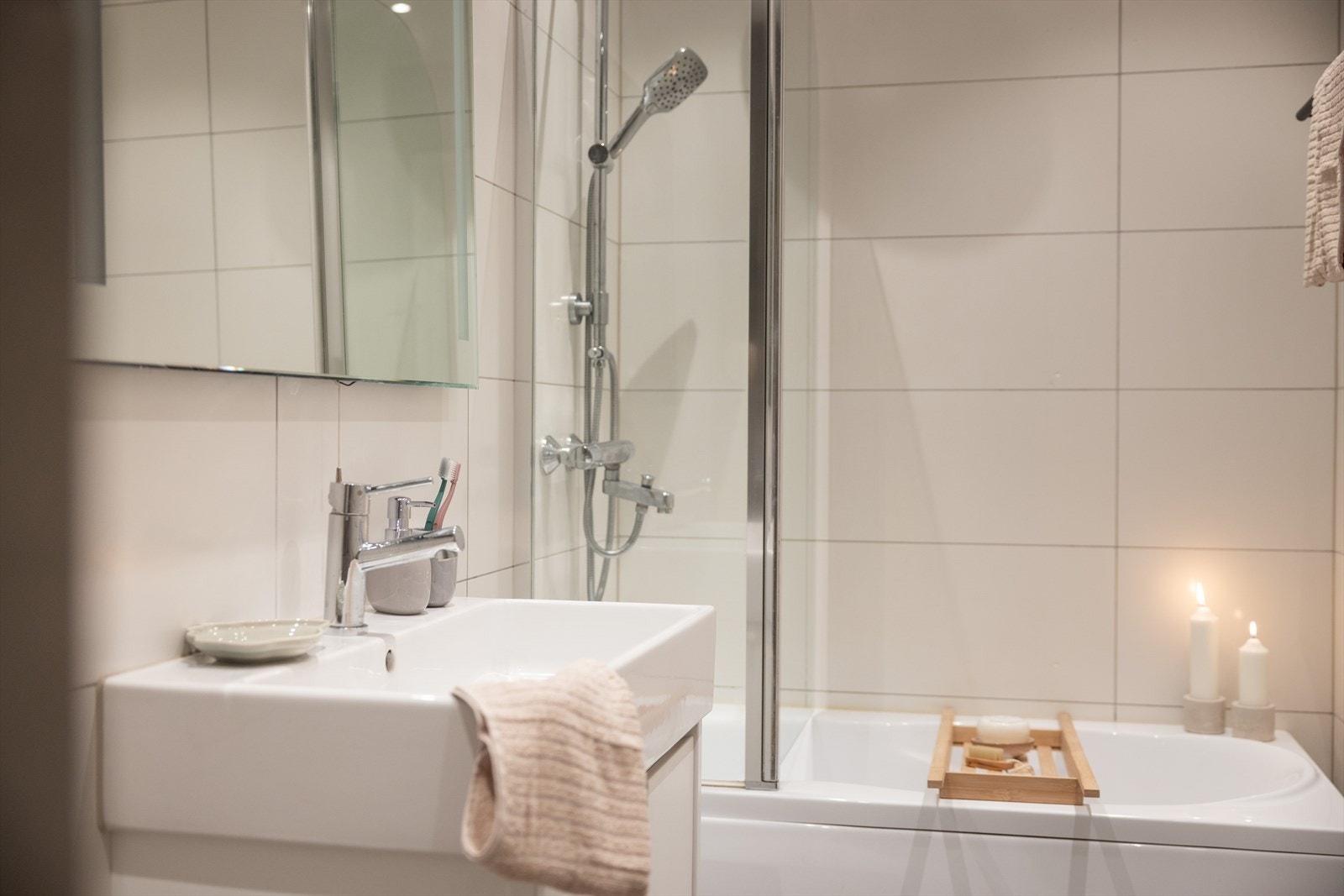 Badet er innredet med vegghengt klosett, servant på innredning og badekar med dusjgarnityr. Galleribilde