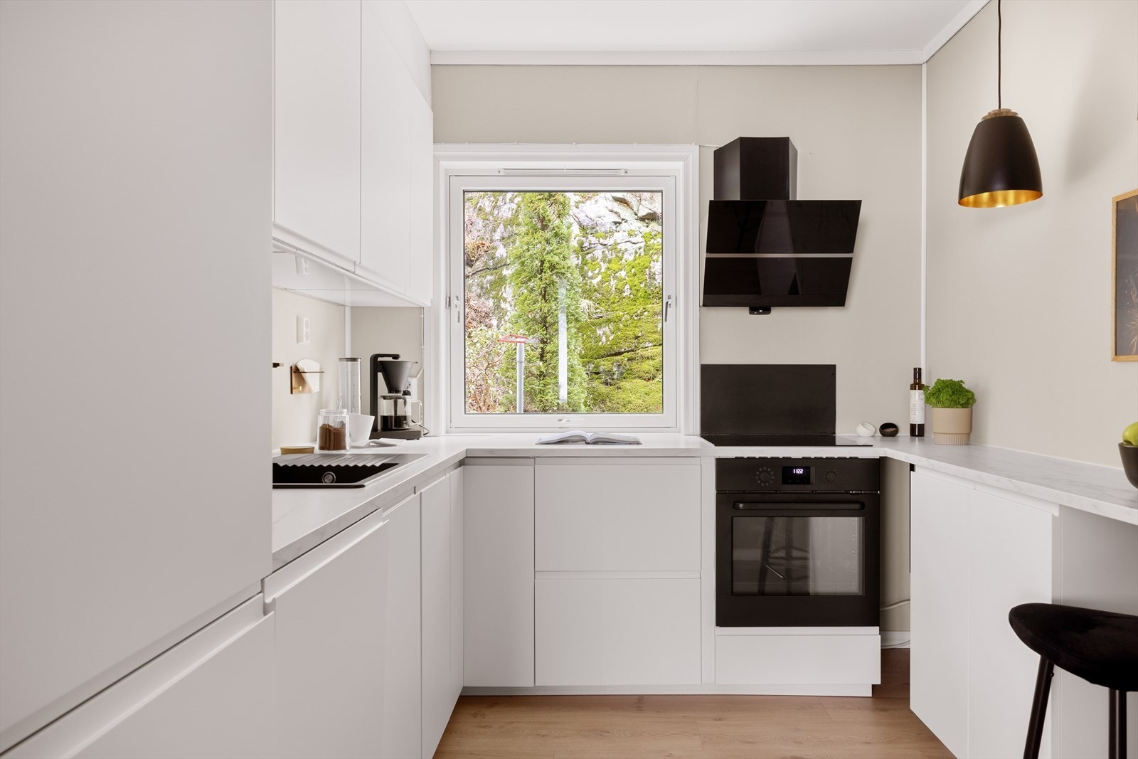 Kjøkkenet er innredet med slette fronter og en laminat benkeplate. Over benkeplaten er det malte flater som gir et stilrent uttrykk. Galleribilde