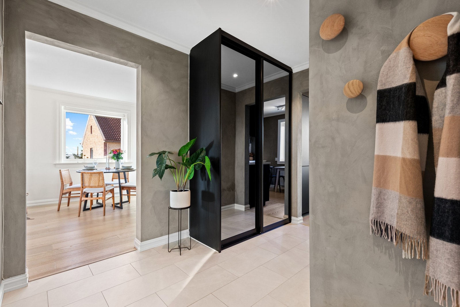 Rommet har dørtelefon ved ytterdøren, knagger på veggen og en stor skyvedørsgarderobe med speilfronter og sort omramming Galleribilde