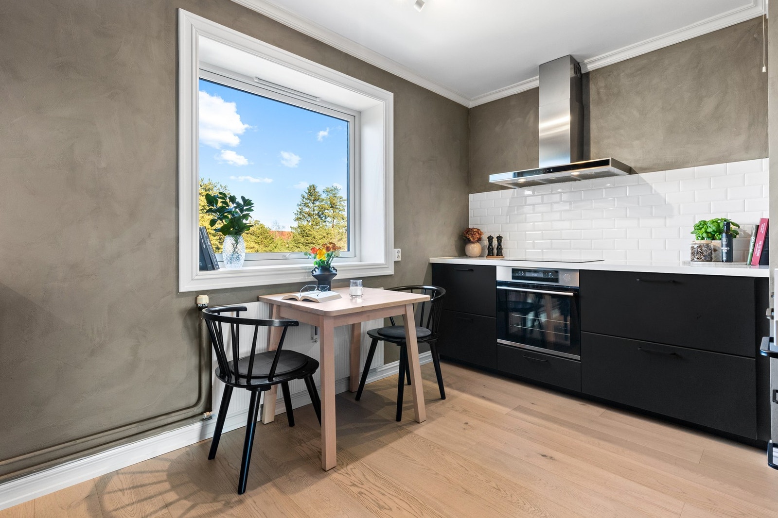 Innredningen har god skapplass og er plassert langs tre sider. Den har takhøye skap, sorte, glatte fronter og hvite benkeplater i laminat med nedfelt vaskekum i kompositt Galleribilde