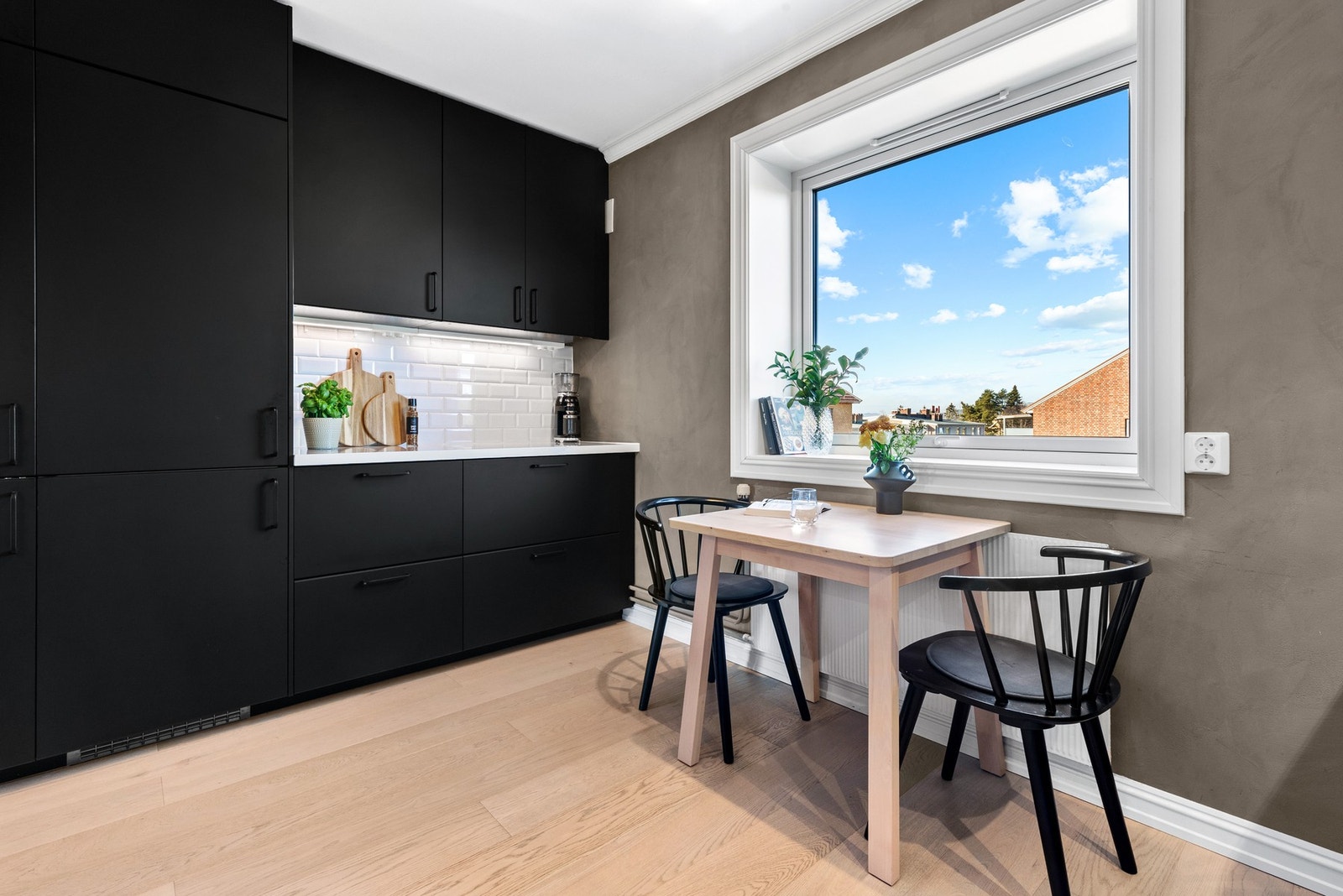 Kjøkkenet har enstavs parkettgulv, vegger malt med stilig kalkmaling, likt som i entreen, og fin plass til et frokostbord ved kjøkkenvinduet Galleribilde