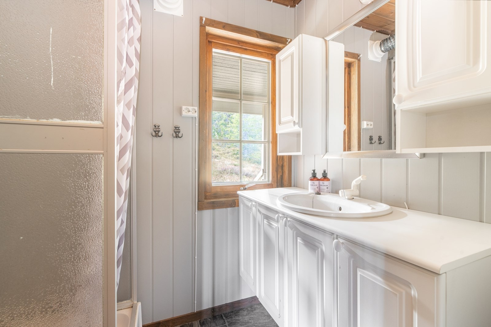 Enkelt bad oppgradert etter 2014 med ny veggpanel og belegg på gulv. Badet har dusjkabinett og innredning med benkeplate og nedfelt vask, under- og overskap med profilerte fronter og speil. Utformet med enkle, men funksjonelle løsninger uten innlagt vann. Galleribilde