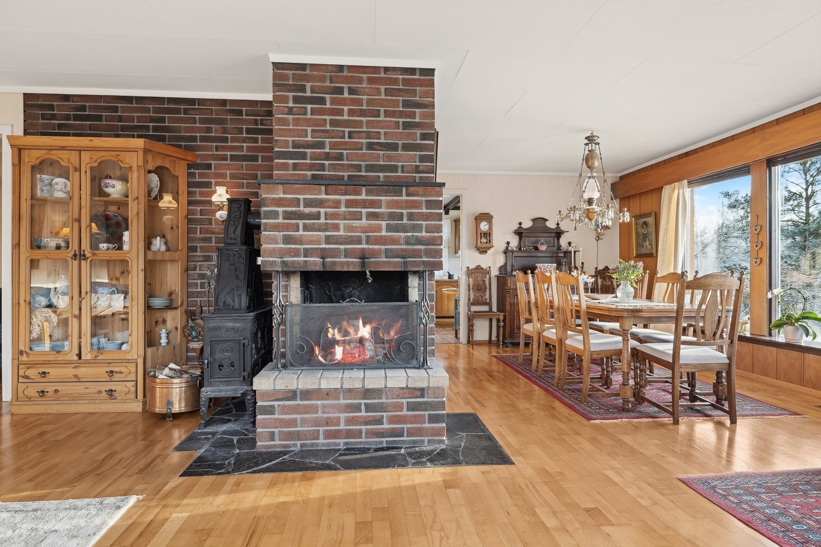 Midt i rommet er det bygd en åpen pei. Nytt ildsted (2010) og energivennlig oppvarming med varmluftkanaler i gulv fra varmluftsanlegg. Galleribilde