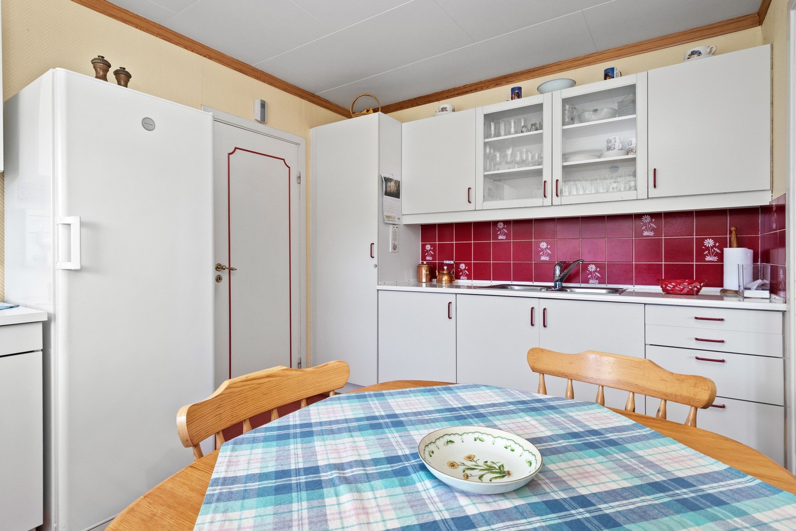 Innredningen har hvite, glatte fronter, vitrineskap og benkeplate av laminat med dobbel oppvaskkum. Galleribilde