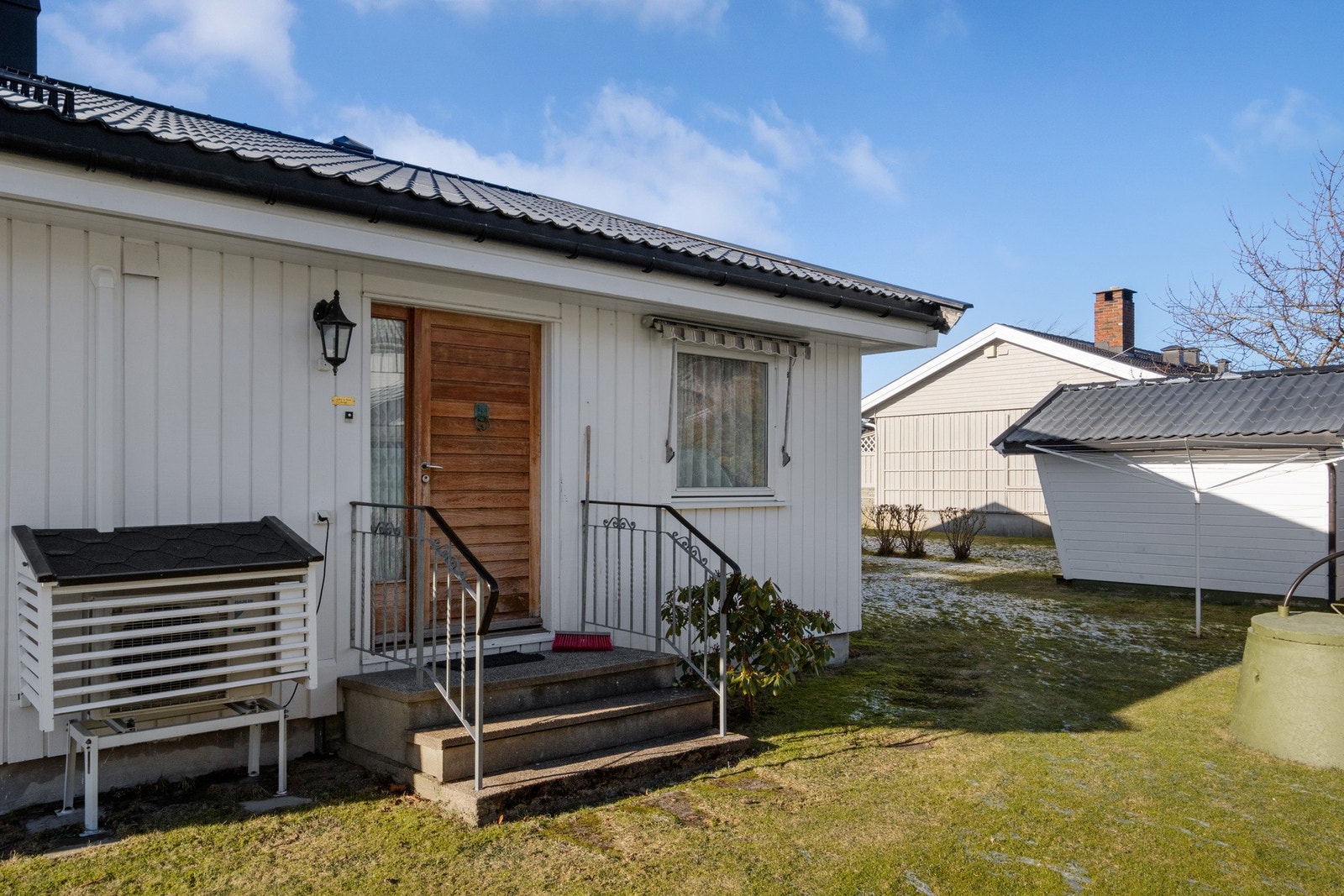 Ytterdøren er overbygd på baksiden av huset, utstyrt med belysning og ringeklokke. Galleribilde