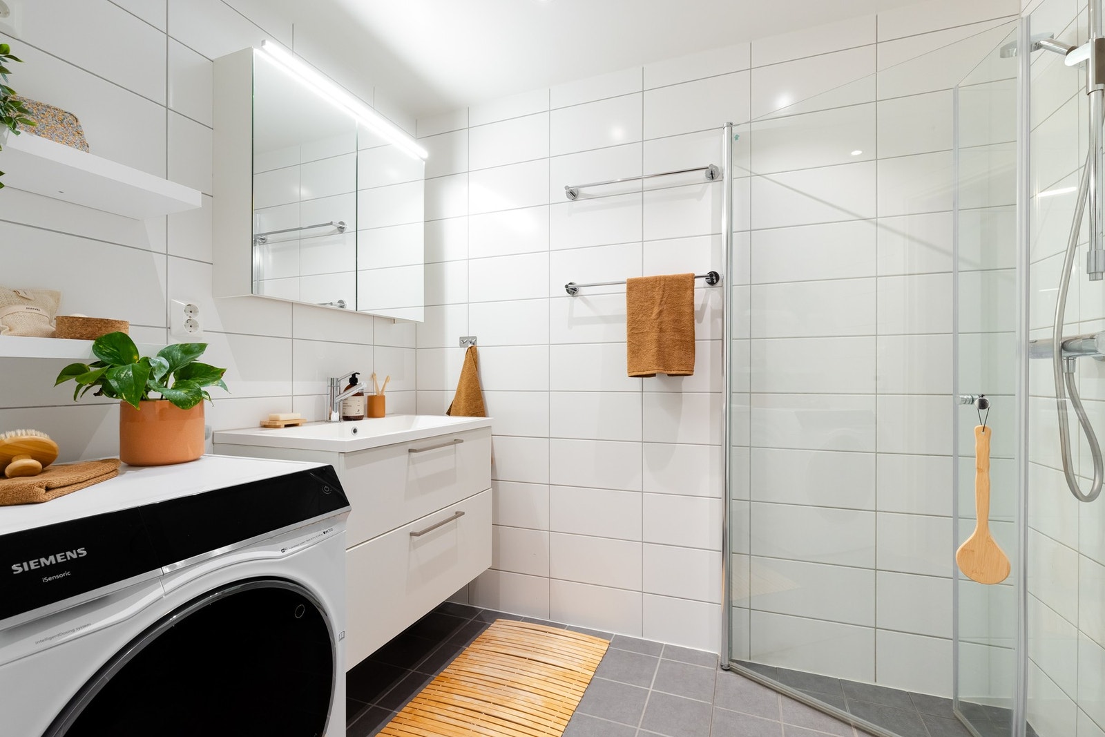 Pent baderom bygget opp med lyse fliser på vegger og grå fliser på gulv Galleribilde