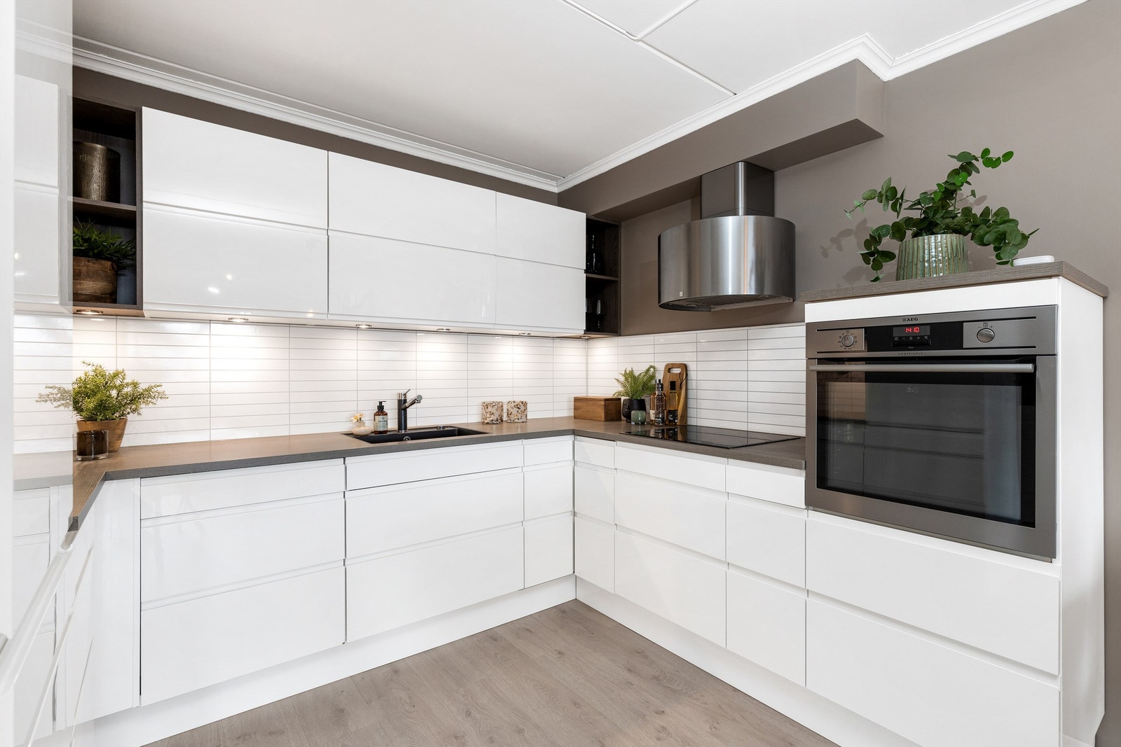 Innredningen er tidløs og stilfull med glatte fronter og laminat benkeplate med nedfelt vaskekum, samt plate og belysning over benkeplaten. Galleribilde