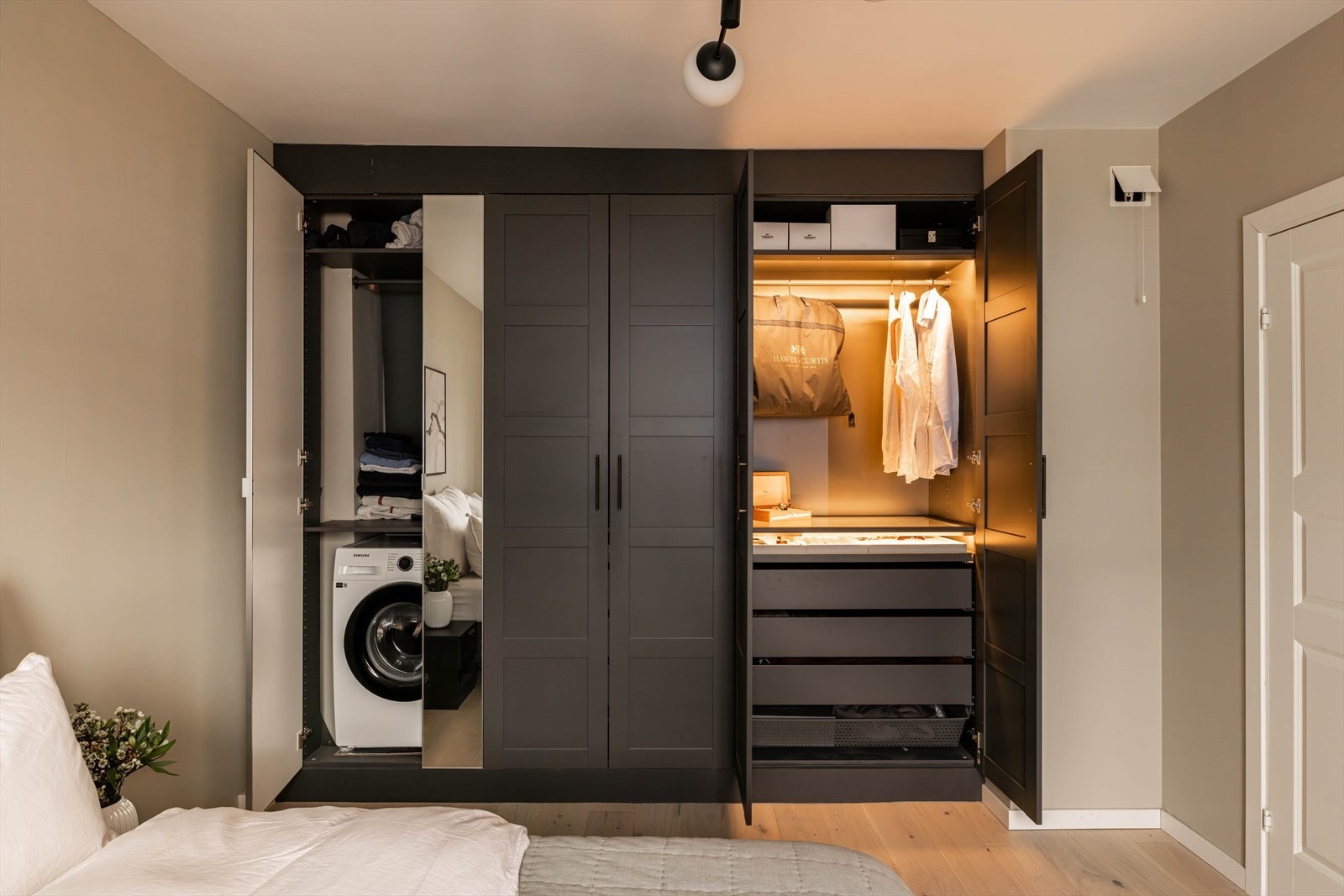 Garderobeskapet er praktisk innredet med opplegg til vaskemaskin og påkostet klesoppheng med lys. Galleribilde