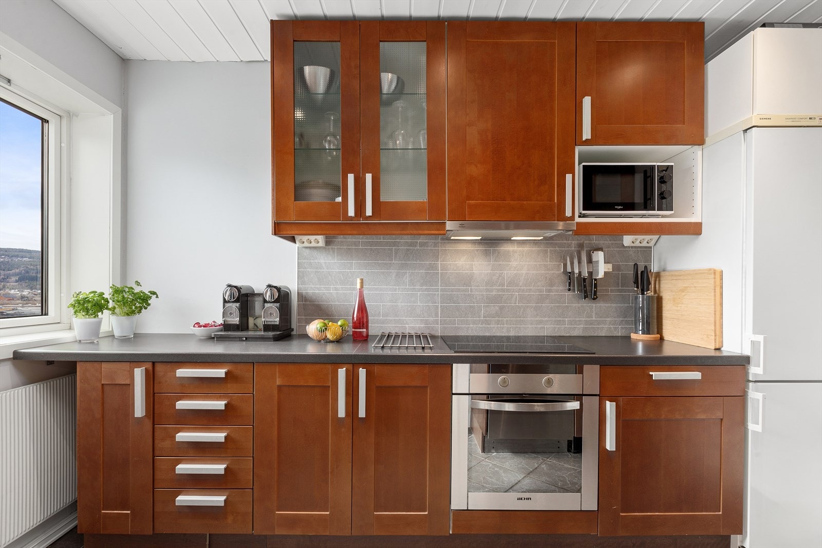 Pent kjøkken bestående av over- og underskap, langskap og skuffer. Pene detaljer med bl.a vitrineskap Galleribilde